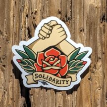 hands holding with a rose at the center and text below in a banner reads "solidarity" sticker made by Samantha Trueblood